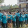 Tim perusahaan sedang melakukan kegiatan outbound training di area hijau Jakarta dengan instruktur profesional memandu aktivitas team building