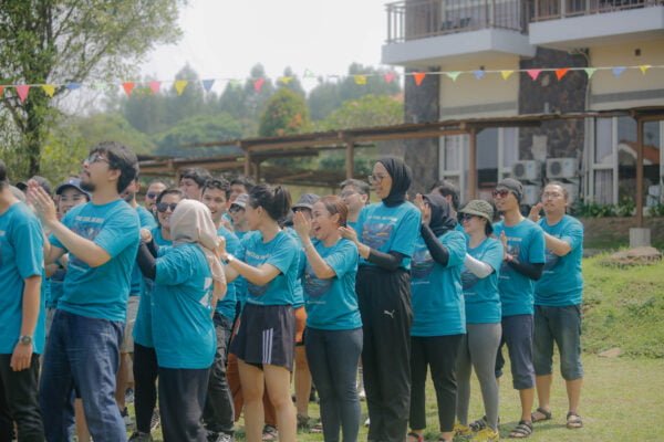 Tim perusahaan sedang melakukan kegiatan outbound training di area hijau Jakarta dengan instruktur profesional memandu aktivitas team building