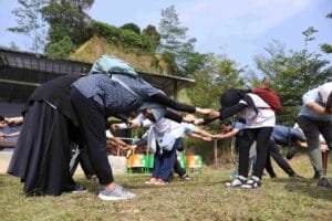 Sekelompok anak muda sedang berkumpul outdoor dalam kegiatan capacity building untuk melatih teamwork dan leadership skill.